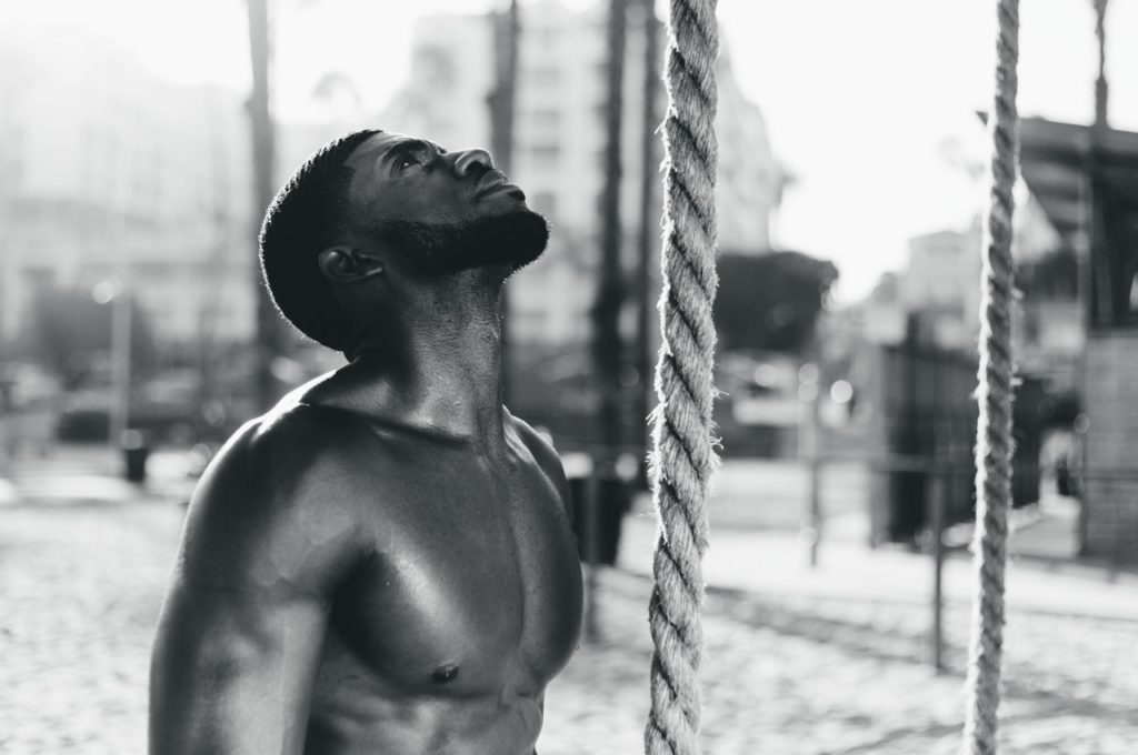 A man trying to climb a rope as part of his workout