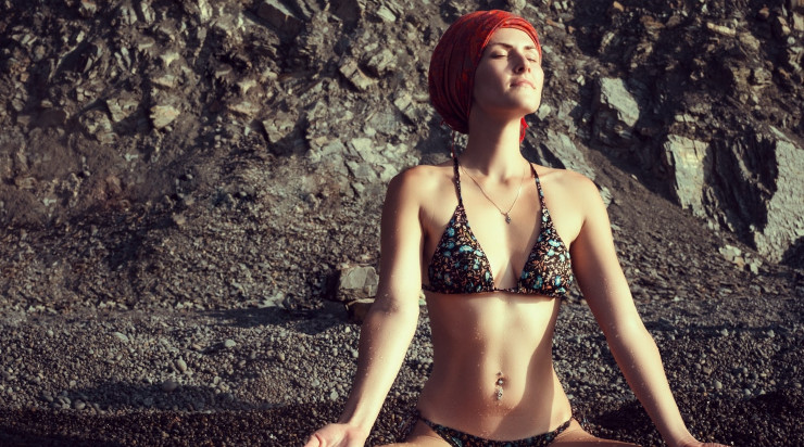 Girl meditating at a rocky beach