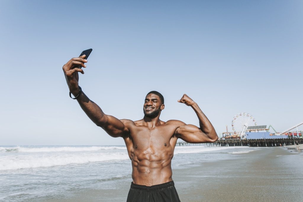 Man taking a selfie and flaunting his body at the beach
