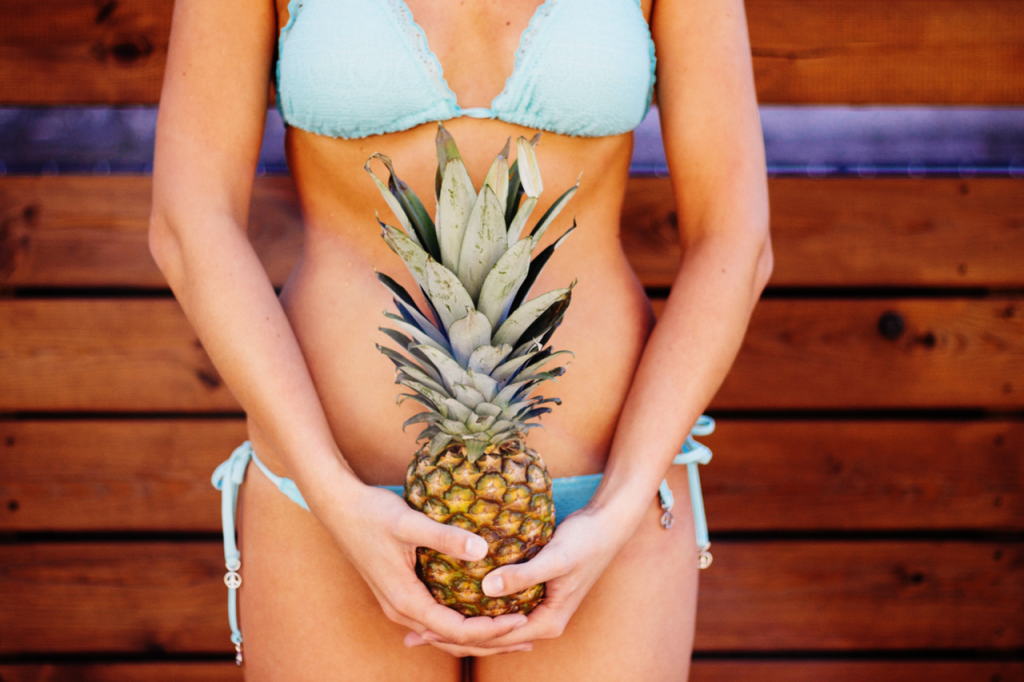 Woman on bathing suit holding pineapple