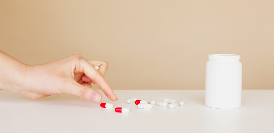 Hand taking pills from a table