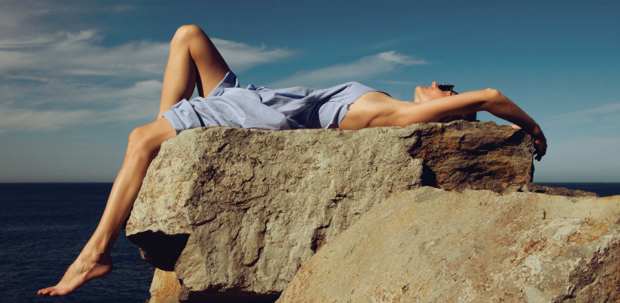 Woman lying down on a rock beside the sea