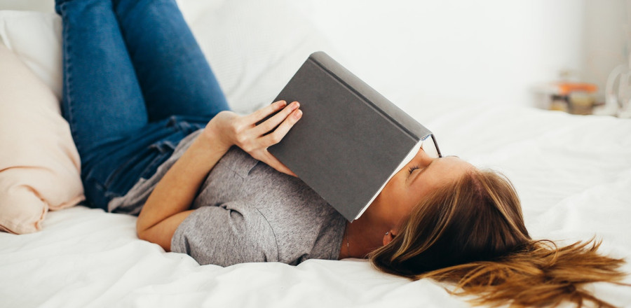 Woman with a book on her bed resting