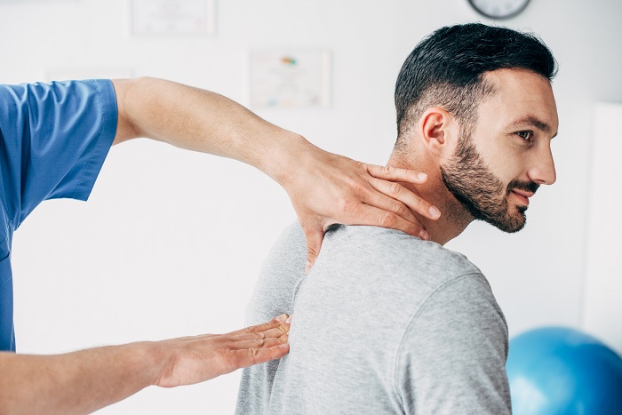 Chiropractor massaging neck of his patient