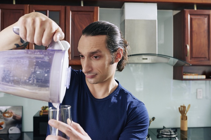 Man pouring protein drink in a glass